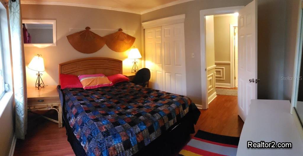A bedroom features a bed with a patterned quilt, two lamps, and wall-mounted fan decorations — 2047 CANAL DRIVE UNIT L6, BRADENTON, FL