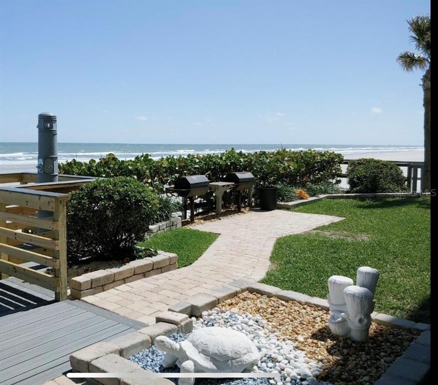 A patio area with grills, a stone turtle statue, and a view of the ocean — 4453 S ATLANTIC AVENUE UNIT 208, PONCE INLET, FL