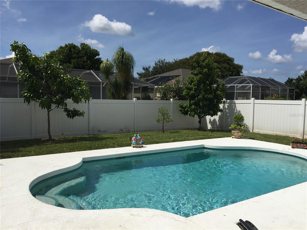 A backyard swimming pool with a white fence and trees under a blue sky — 5010 44TH STREET W, BRADENTON, FL