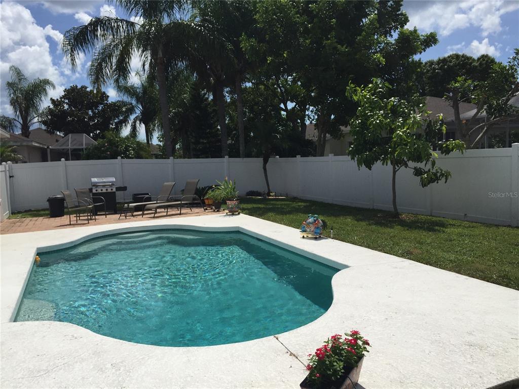 A backyard features a swimming pool, a patio with lounge chairs, and a white fence — 5010 44TH STREET W, BRADENTON, FL