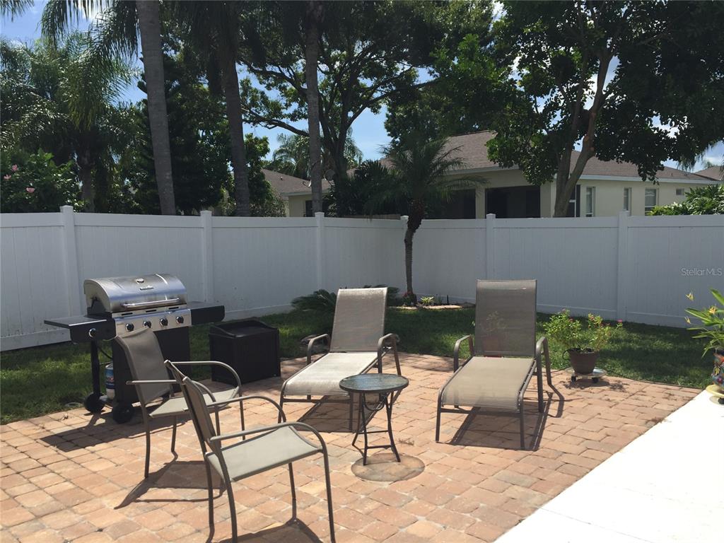 A backyard patio features a grill, two lounge chairs, two dining chairs, and a small table — 5010 44TH STREET W, BRADENTON, FL