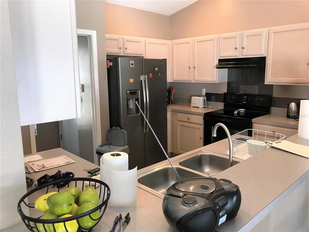A kitchen features white cabinets, stainless steel appliances, a double sink, and a breakfast bar — 5010 44TH STREET W, BRADENTON, FL