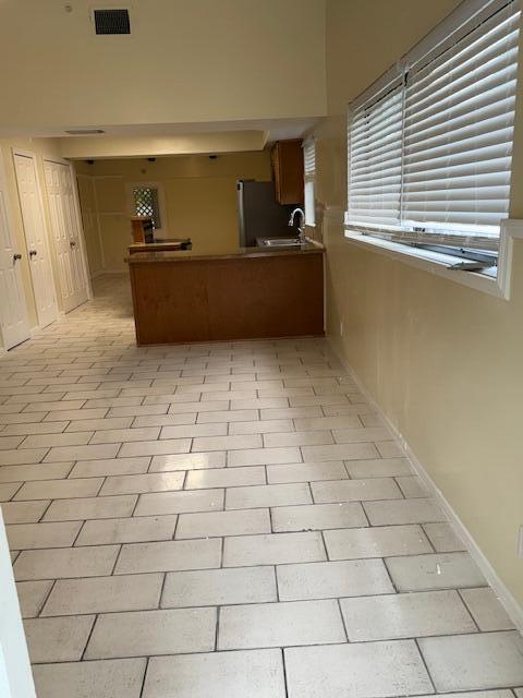 A kitchen with a wooden breakfast bar, tiled floors, and a window with white blinds — 2899 NE 2nd Avenue, Boca Raton FL 33431, BOCA RATON, FL