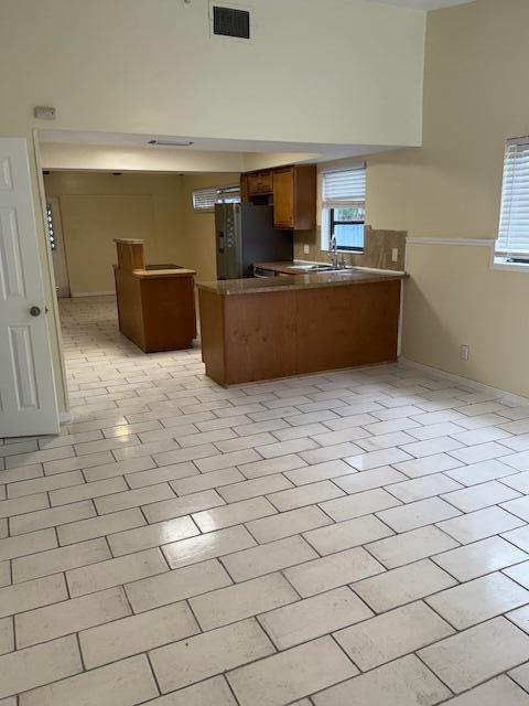 A kitchen with wooden cabinets and a breakfast bar overlooks a tiled living area — 2899 NE 2nd Avenue, Boca Raton FL 33431, BOCA RATON, FL