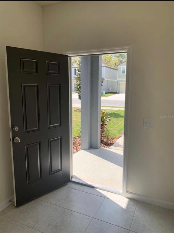 An open black front door reveals a concrete porch and a view of a neighborhood — 2257 LITCHFIELD LOOP, DELAND, FL