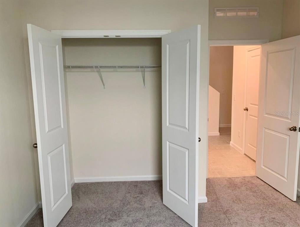 A room with gray carpet, an open closet with a shelf, and an adjacent doorway — 2257 LITCHFIELD LOOP, DELAND, FL