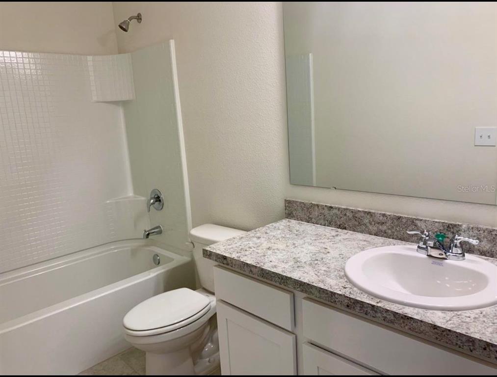 A bathroom features a white tub-shower combo, a toilet, and a vanity with granite countertops — 2257 LITCHFIELD LOOP, DELAND, FL