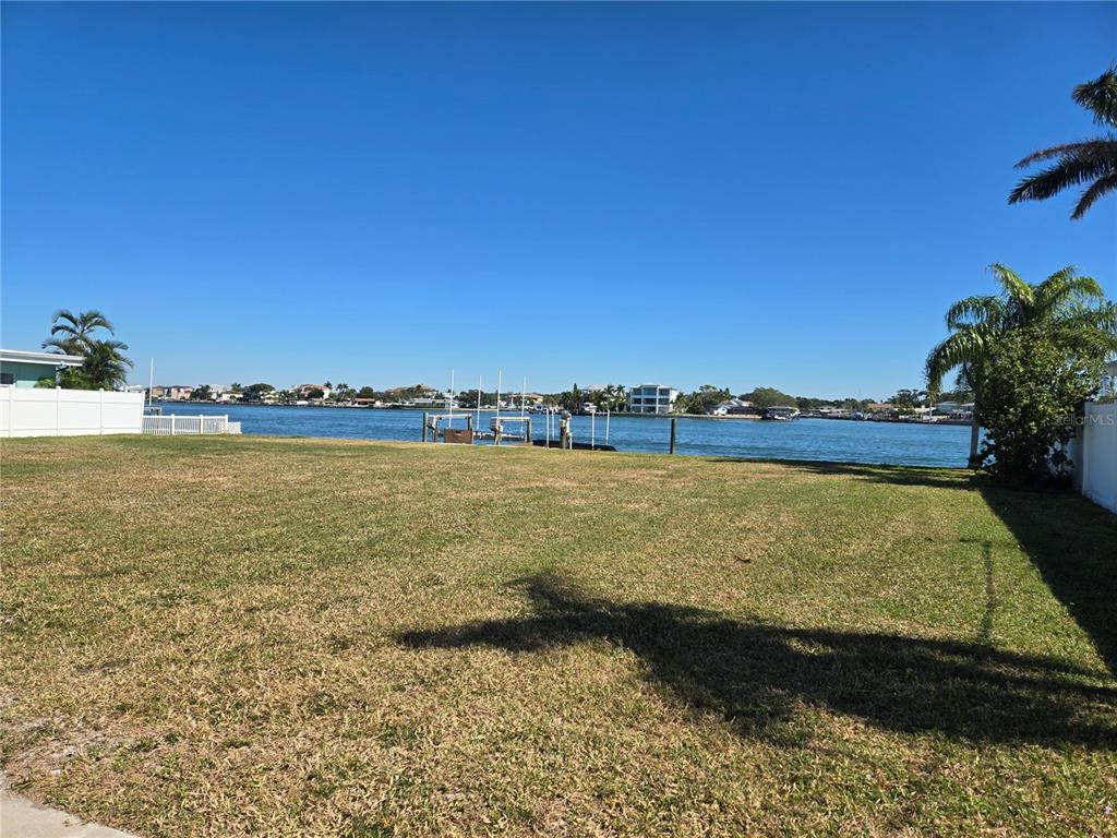 A grassy waterfront lot features a private dock extending into the bay — 512 20TH AVENUE, INDIAN ROCKS BEACH, FL