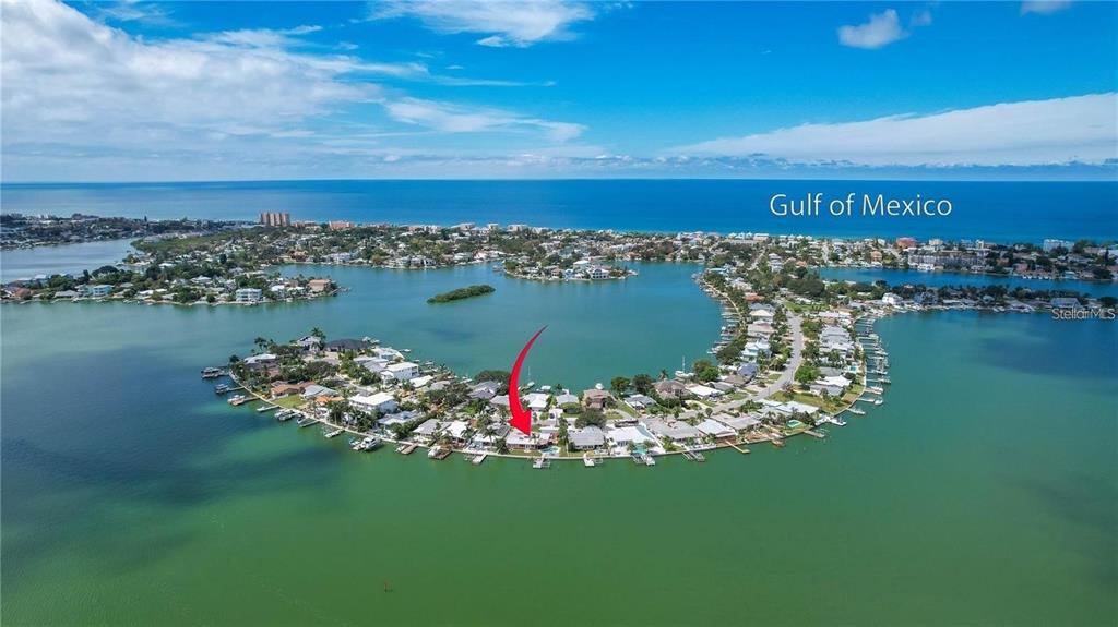 An aerial view shows a waterfront house on a peninsula with a private boat dock — 512 20TH AVENUE, INDIAN ROCKS BEACH, FL
