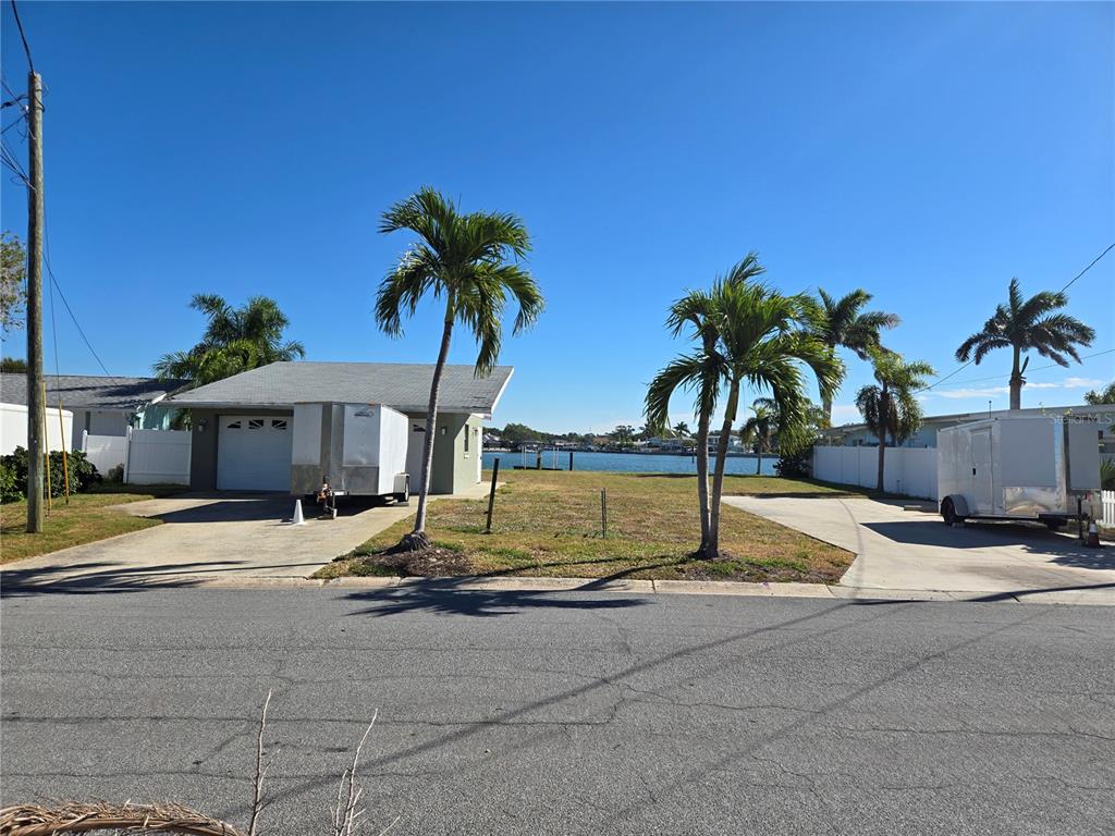 A waterfront lot features a garage, two palm trees, and two trailers on concrete driveways — 512 20TH AVENUE, INDIAN ROCKS BEACH, FL