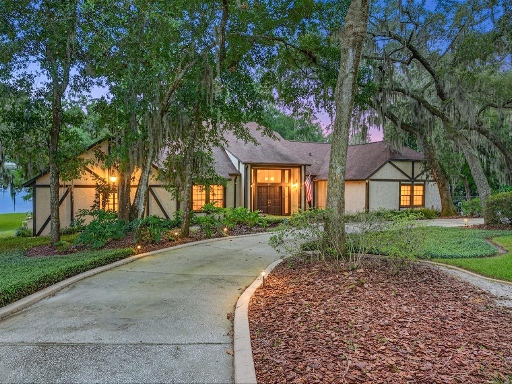 A curved concrete driveway leads to a single-story house with Tudor-style trim and mature trees — 671 QUIETWATER COVE, ALTAMONTE SPRINGS, FL