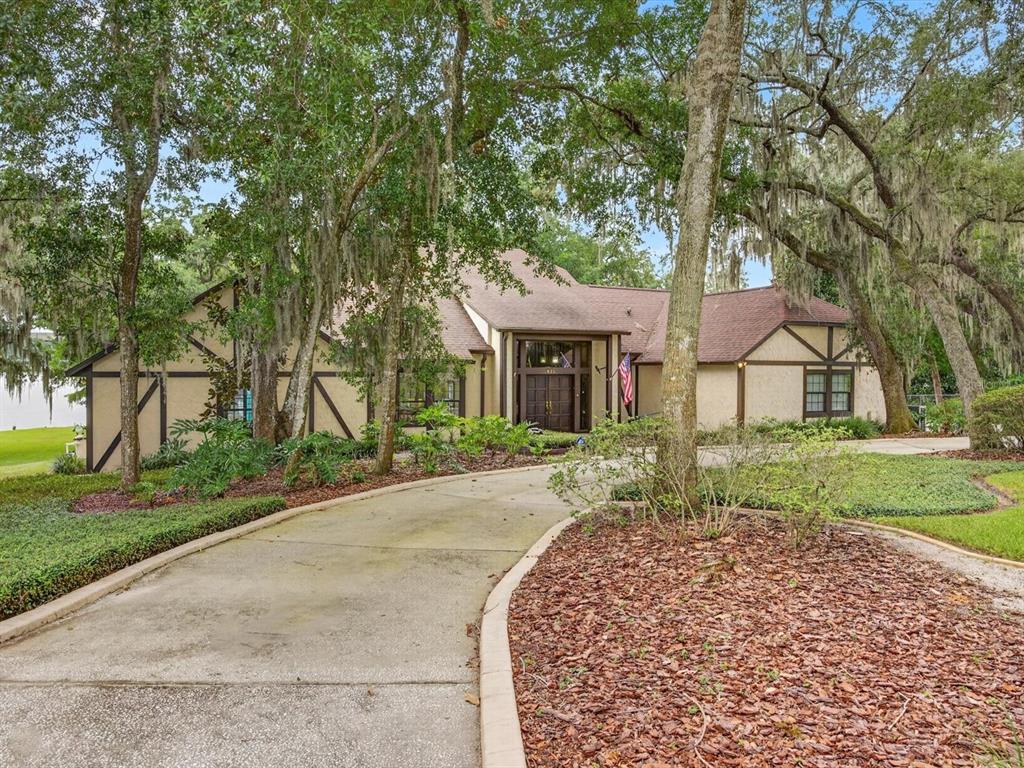 A curved concrete driveway leads to the front entrance of a single-story Tudor-style home — 671 QUIETWATER COVE, ALTAMONTE SPRINGS, FL