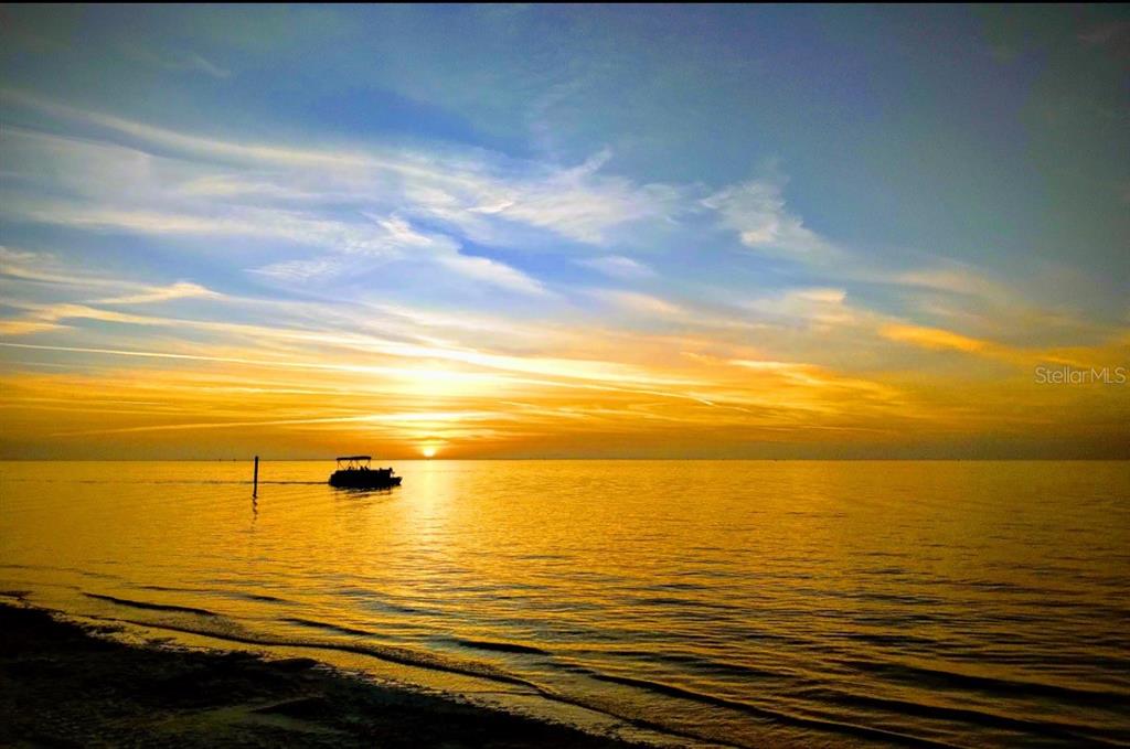 A boat floats on a calm body of water during a vibrant golden sunset — 5245 AMULET DRIVE UNIT 102, NEW PORT RICHEY, FL