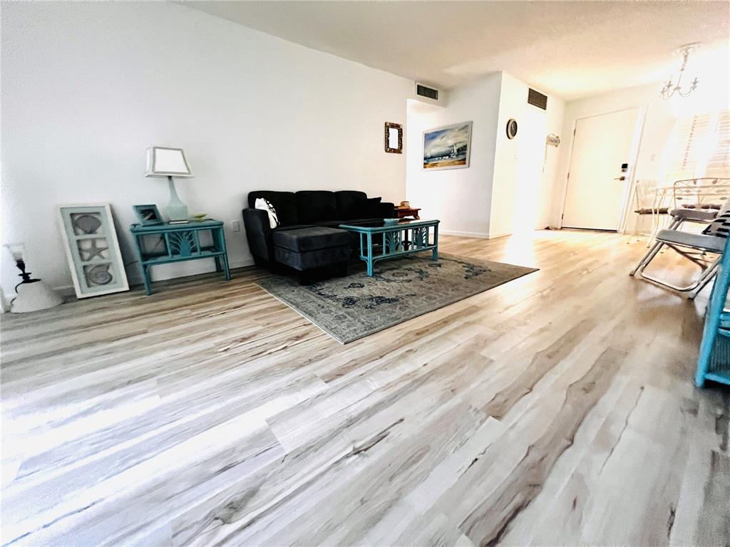 A living room features light wood-look flooring, a dark sofa, and teal accent furniture — 5245 AMULET DRIVE UNIT 102, NEW PORT RICHEY, FL