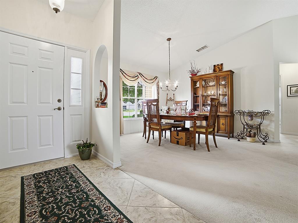 A dining room with a wooden hutch and table sits adjacent to a tiled entryway — 25069 RIVERWALK DRIVE, LEESBURG, FL