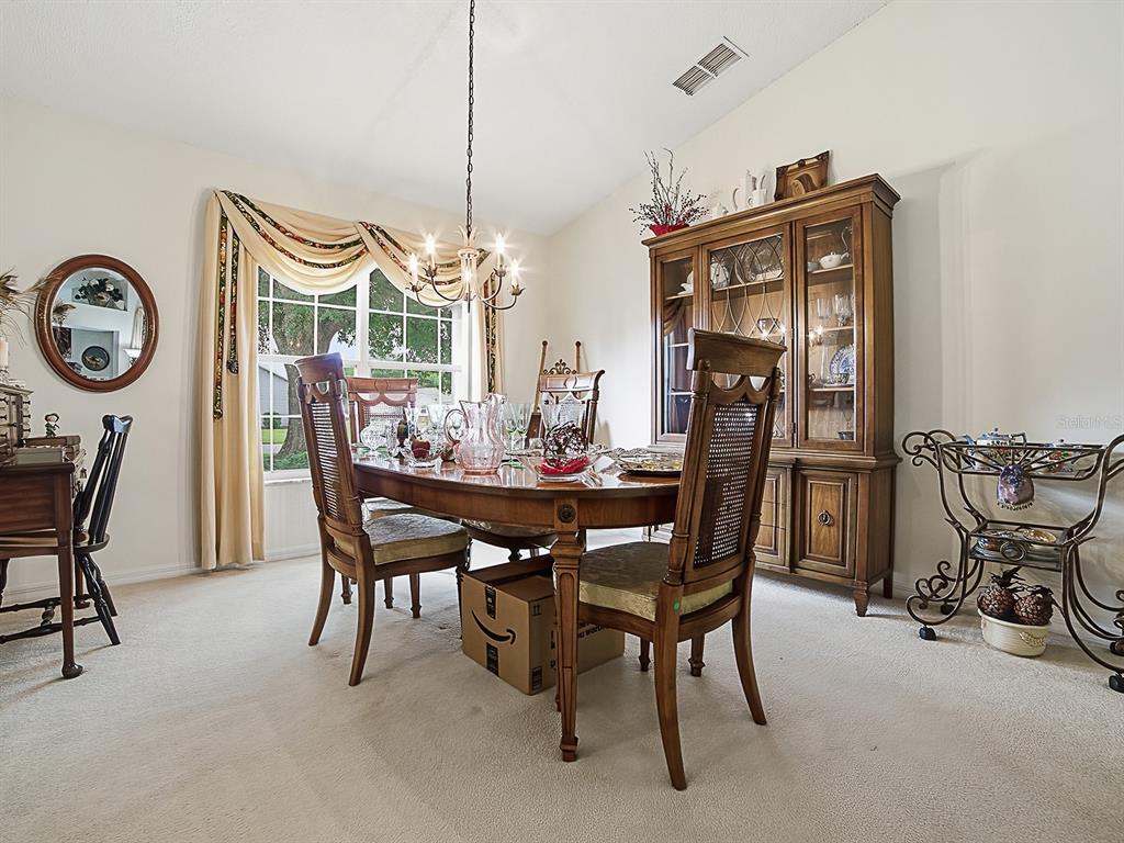 A dining room features a wooden table with chairs, a hutch, and a chandelier — 25069 RIVERWALK DRIVE, LEESBURG, FL