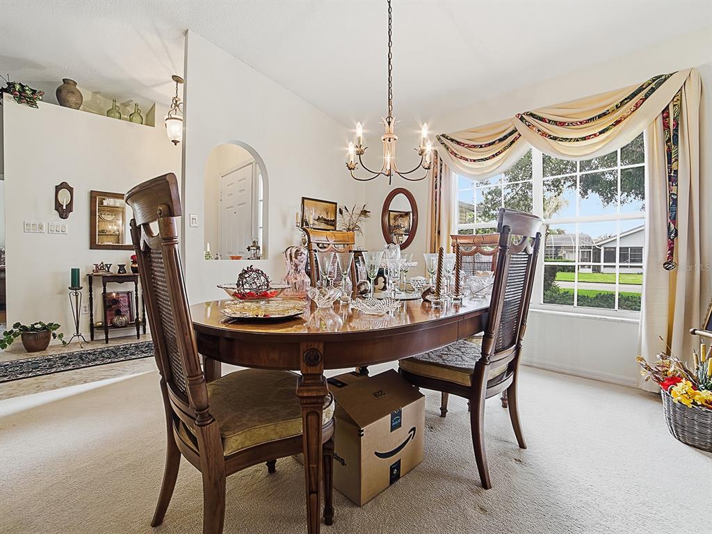 A dining room features a wooden table with chairs, a chandelier, and a large window — 25069 RIVERWALK DRIVE, LEESBURG, FL