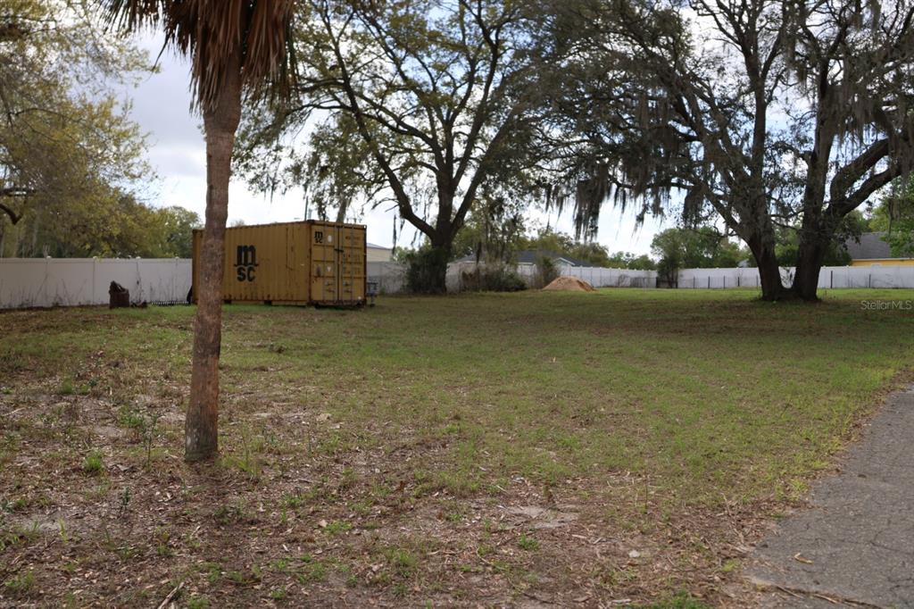 A large, grassy vacant lot features a yellow shipping container and several mature trees — 11234 SE 121ST LANE ROAD, BELLEVIEW, FL