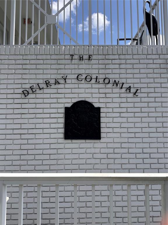 A white brick wall features the black metal lettering "The Delray Colonial" and a plaque — 1001 NE 8TH AVENUE UNIT 209, DELRAY BEACH, FL