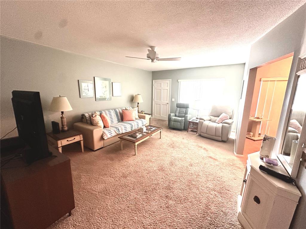 A living room with beige carpet, a sofa, two armchairs, and a ceiling fan — 1001 NE 8TH AVENUE UNIT 209, DELRAY BEACH, FL