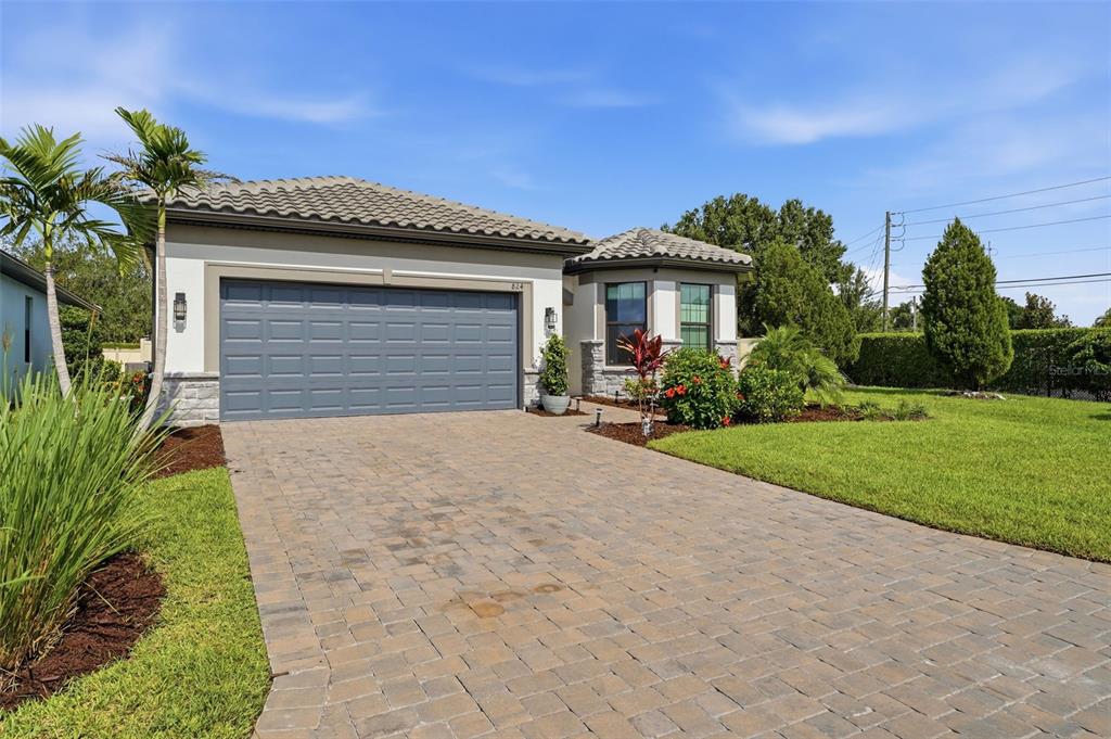 A single-story house with a gray garage door, stone accents, and a paved driveway — 824 GADWALL COURT, BRADENTON, FL