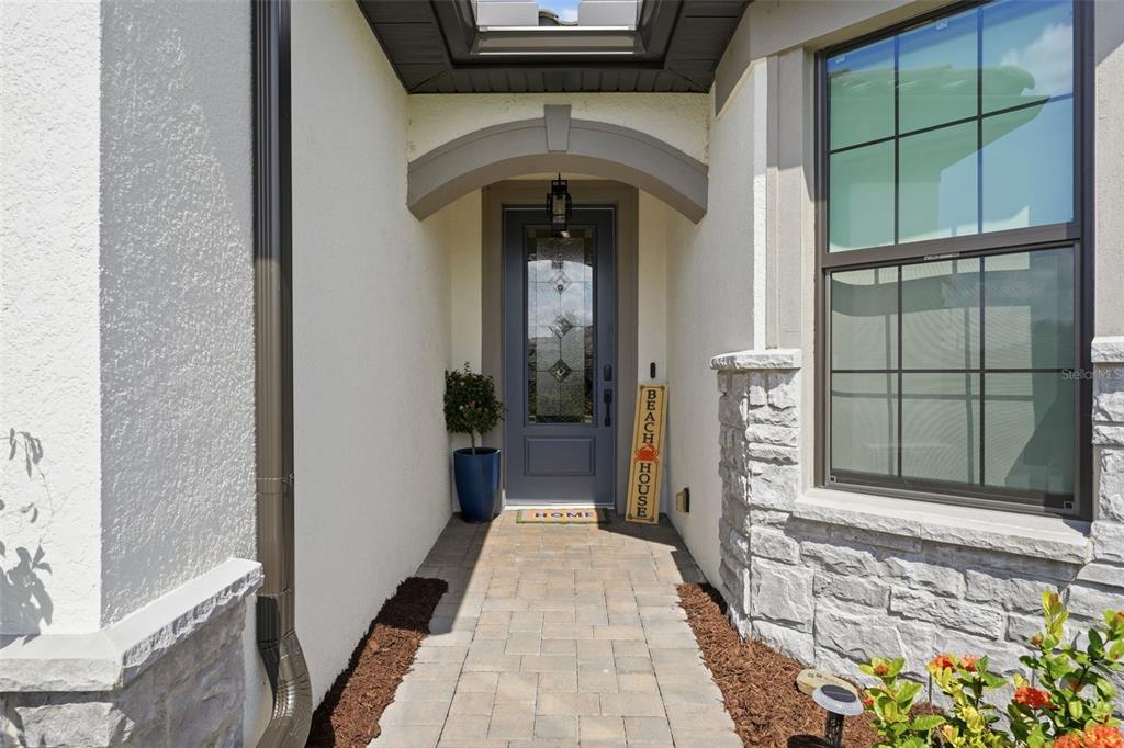 A paved walkway leads to a gray front door under a covered entryway — 824 GADWALL COURT, BRADENTON, FL