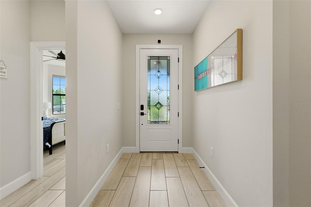 A bright entryway features light wood-look tile flooring, a white front door, and wall art — 824 GADWALL COURT, BRADENTON, FL