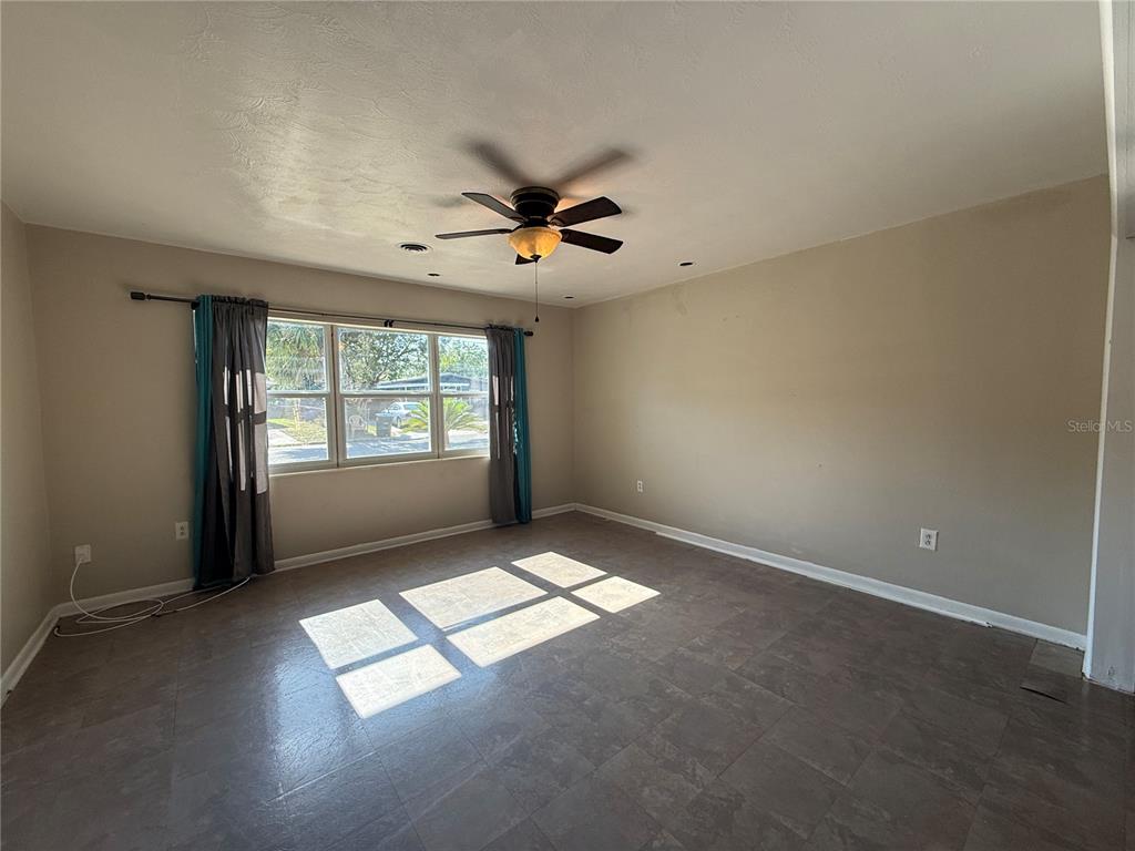 A living room with wood-look flooring, a ceiling fan, and open doorways to other rooms — 915 14TH STREET E, BRADENTON, FL