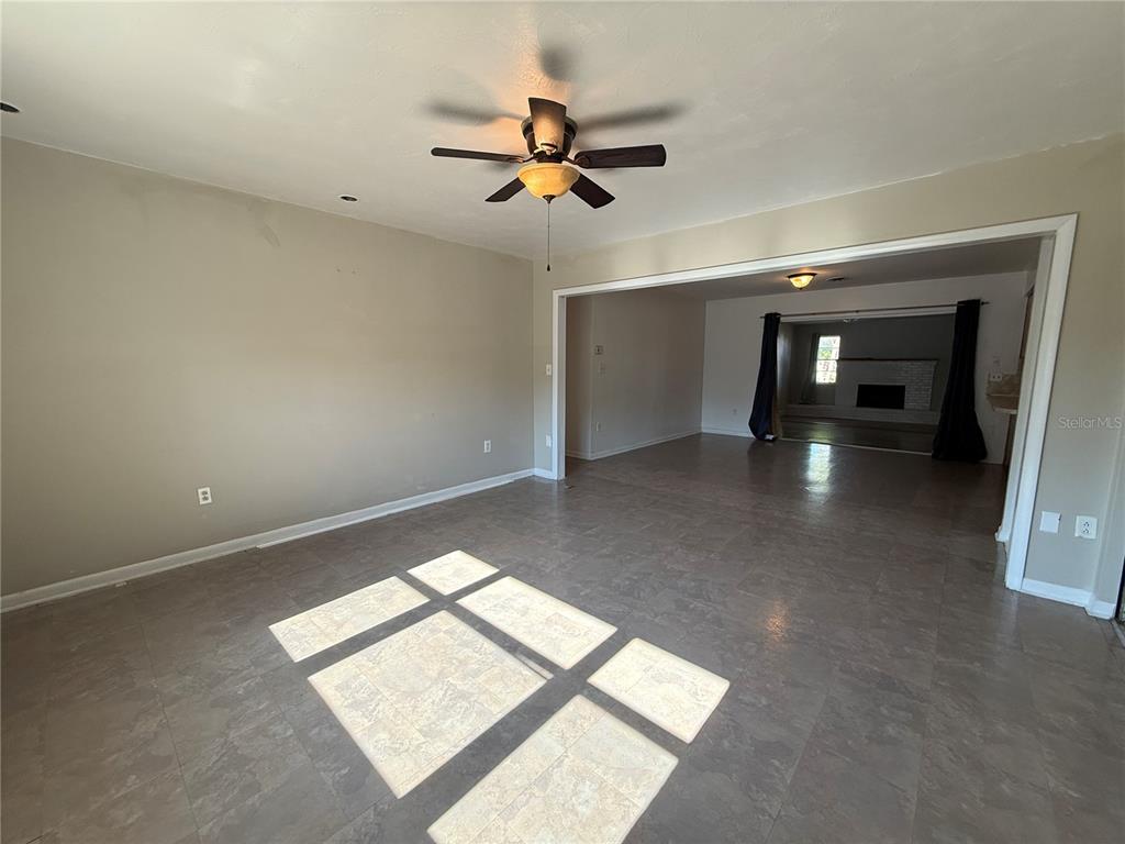 An empty living room features wood-look flooring, a ceiling fan, and built-in wall shelving — 915 14TH STREET E, BRADENTON, FL