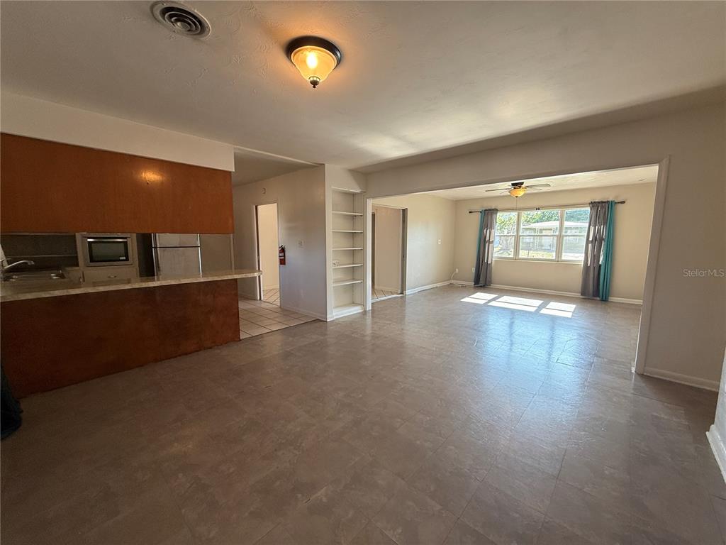 A living room with wood-look flooring opens to a kitchen with stainless steel appliances — 915 14TH STREET E, BRADENTON, FL