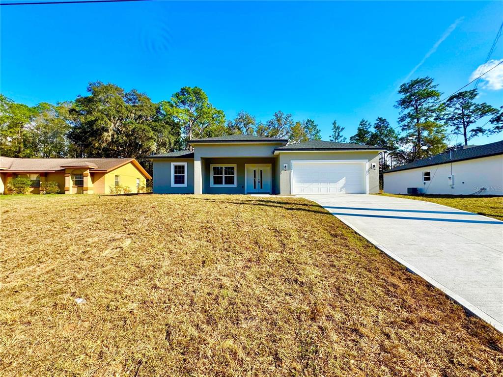 A single-story gray house with a white garage door and a concrete driveway — 10385 N CITRUS SPRINGS BOULEVARD, CITRUS SPRINGS, FL