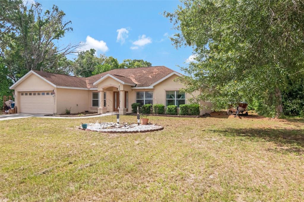 A single-story tan house with a two-car garage and a front yard with landscaping — 12276 VILLA ROAD, SPRING HILL, FL