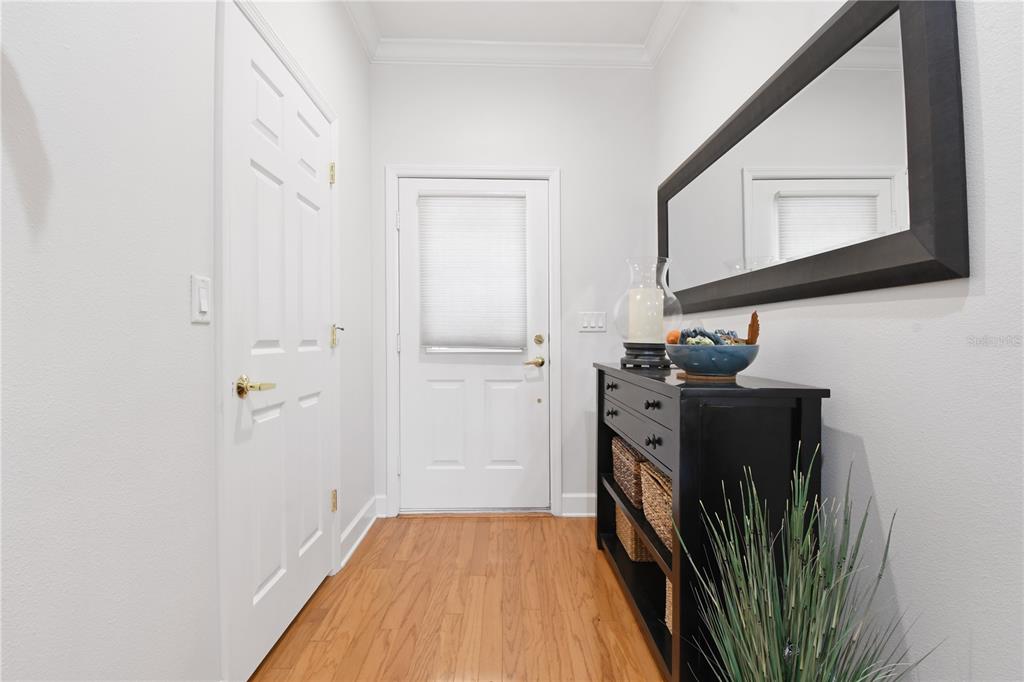 A bright entryway features wood flooring, a white door, a black console table, and a mirror — 2650 TANGLEWOOD TRAIL, PALM HARBOR, FL