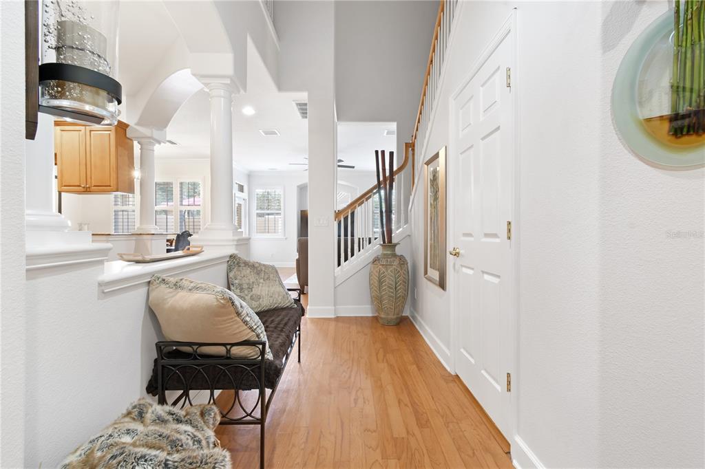 A bright entryway features hardwood floors, a bench, a staircase, and a view into a kitchen — 2650 TANGLEWOOD TRAIL, PALM HARBOR, FL