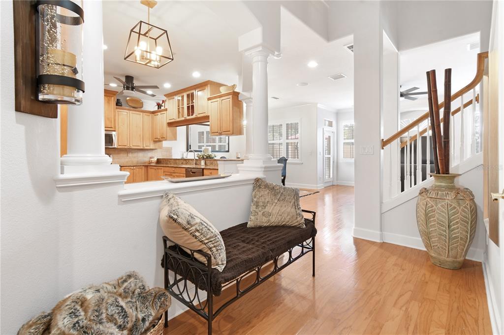 A foyer with a bench and staircase leads into an open-concept kitchen with wood cabinets — 2650 TANGLEWOOD TRAIL, PALM HARBOR, FL