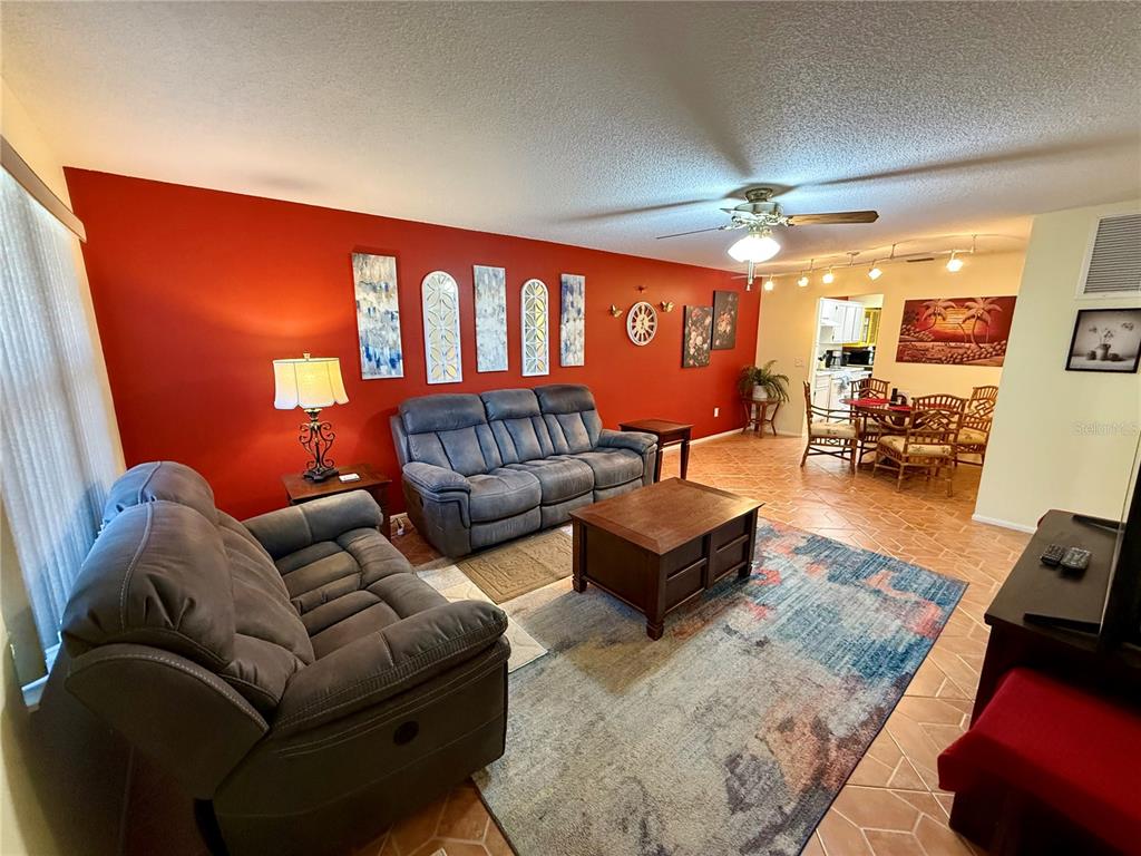 A living room with a red accent wall, gray sofas, and a patterned area rug — 6070 80TH STREET N UNIT 105, ST PETERSBURG, FL