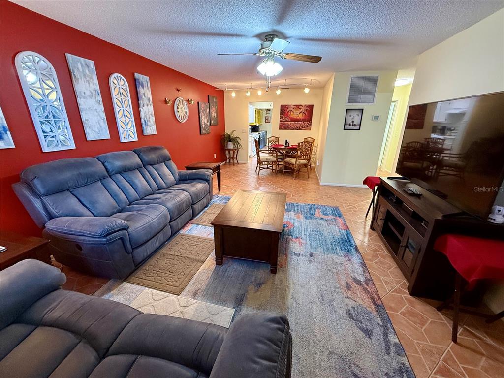 A living room features a red accent wall, blue sofa, and a large area rug — 6070 80TH STREET N UNIT 105, ST PETERSBURG, FL
