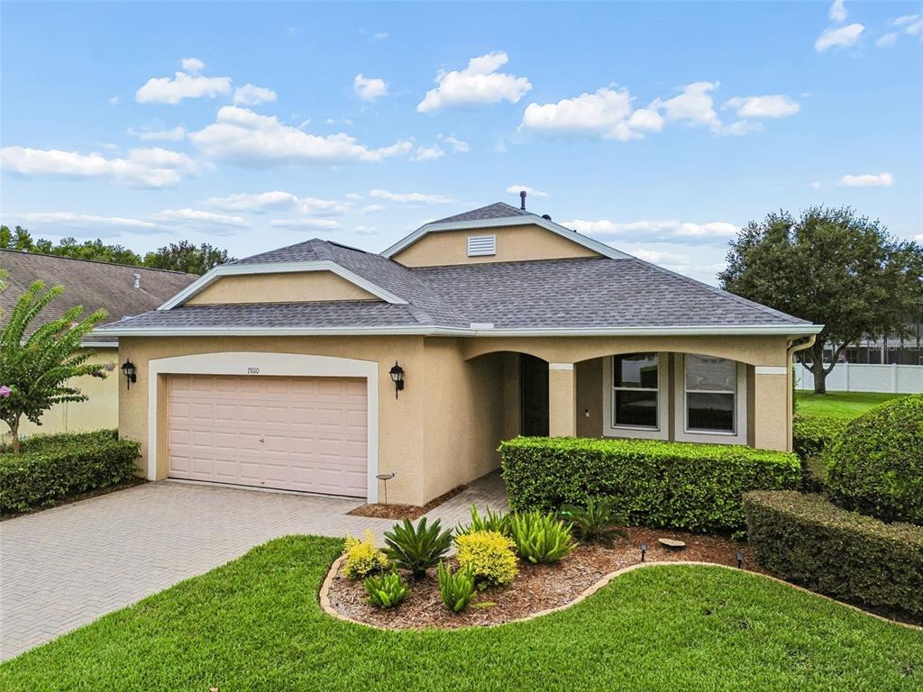 A single-story house with a tan stucco exterior, a two-car garage, and a landscaped yard — 19110 SUNSET BAY DRIVE, LAND O LAKES, FL