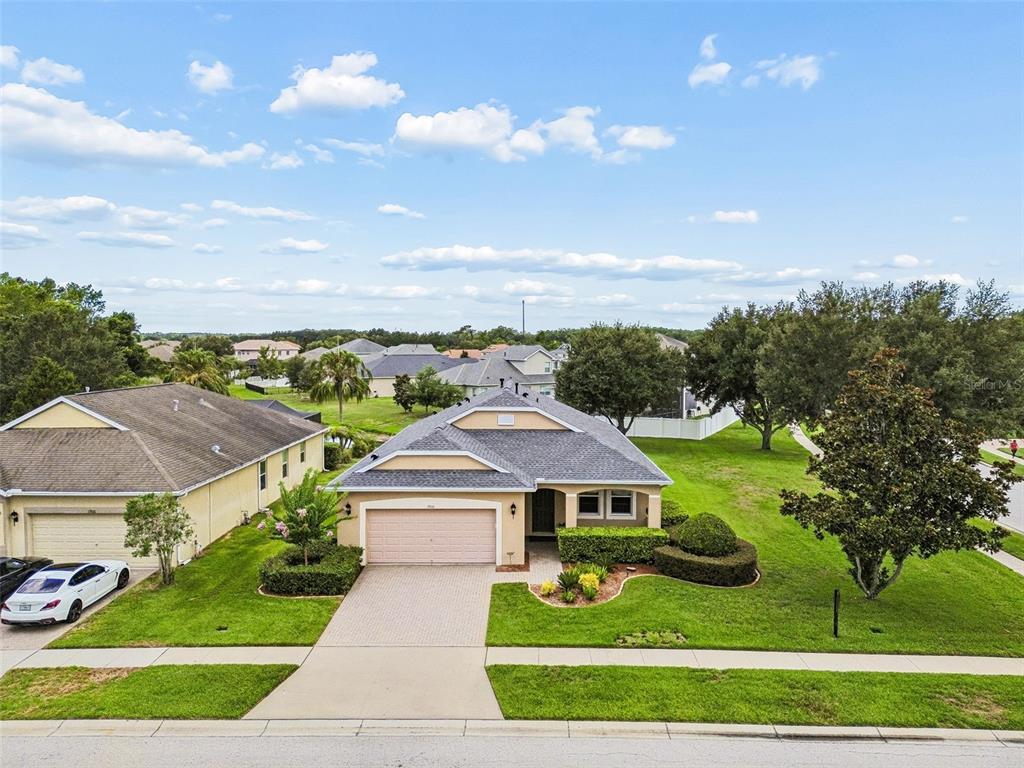 An aerial view shows a single-story suburban house with a two-car garage and landscaped yard — 19110 SUNSET BAY DRIVE, LAND O LAKES, FL