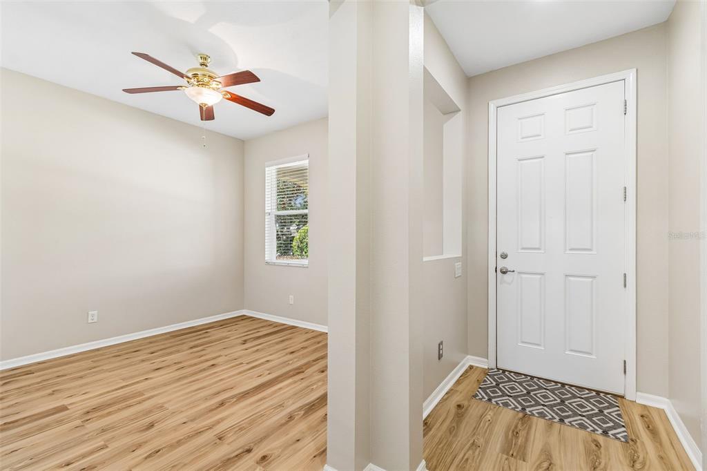 An entryway with a white door and wood-look flooring leads into a room with a ceiling fan — 19110 SUNSET BAY DRIVE, LAND O LAKES, FL