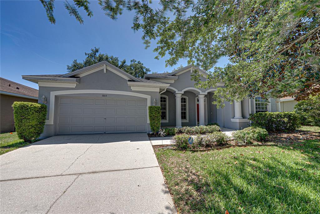 A blue single-story house with a two-car garage and a concrete driveway — 1603 GRAND HERITAGE BOULEVARD, VALRICO, FL