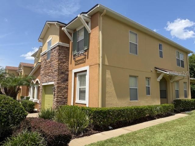 A multi-story residential building features tan stucco walls, stone accents, and a green-trimmed window — 599 LAKE EAGLE LANE, SANFORD, FL