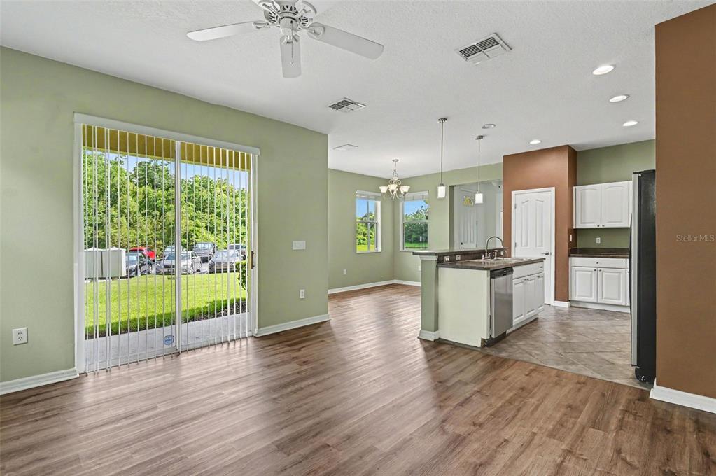 An open-concept living area features wood-look flooring, a kitchen island, and sliding glass patio doors — 599 LAKE EAGLE LANE, SANFORD, FL