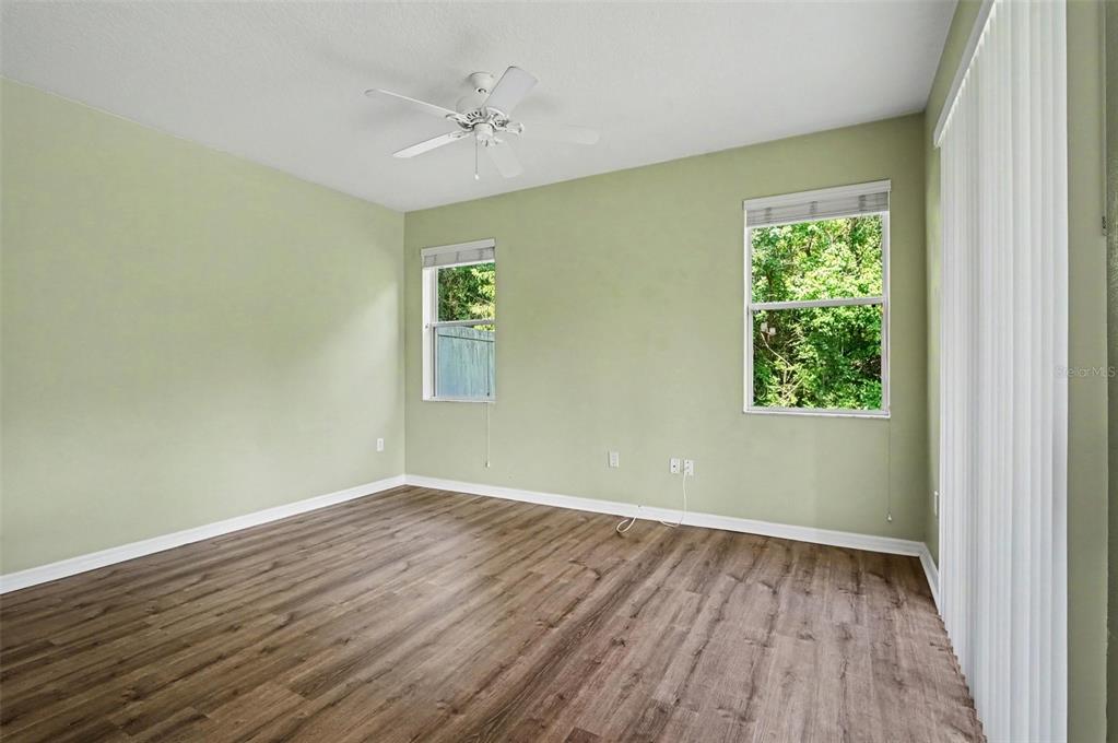 An empty room with light green walls, wood-look flooring, a ceiling fan, and two windows — 599 LAKE EAGLE LANE, SANFORD, FL