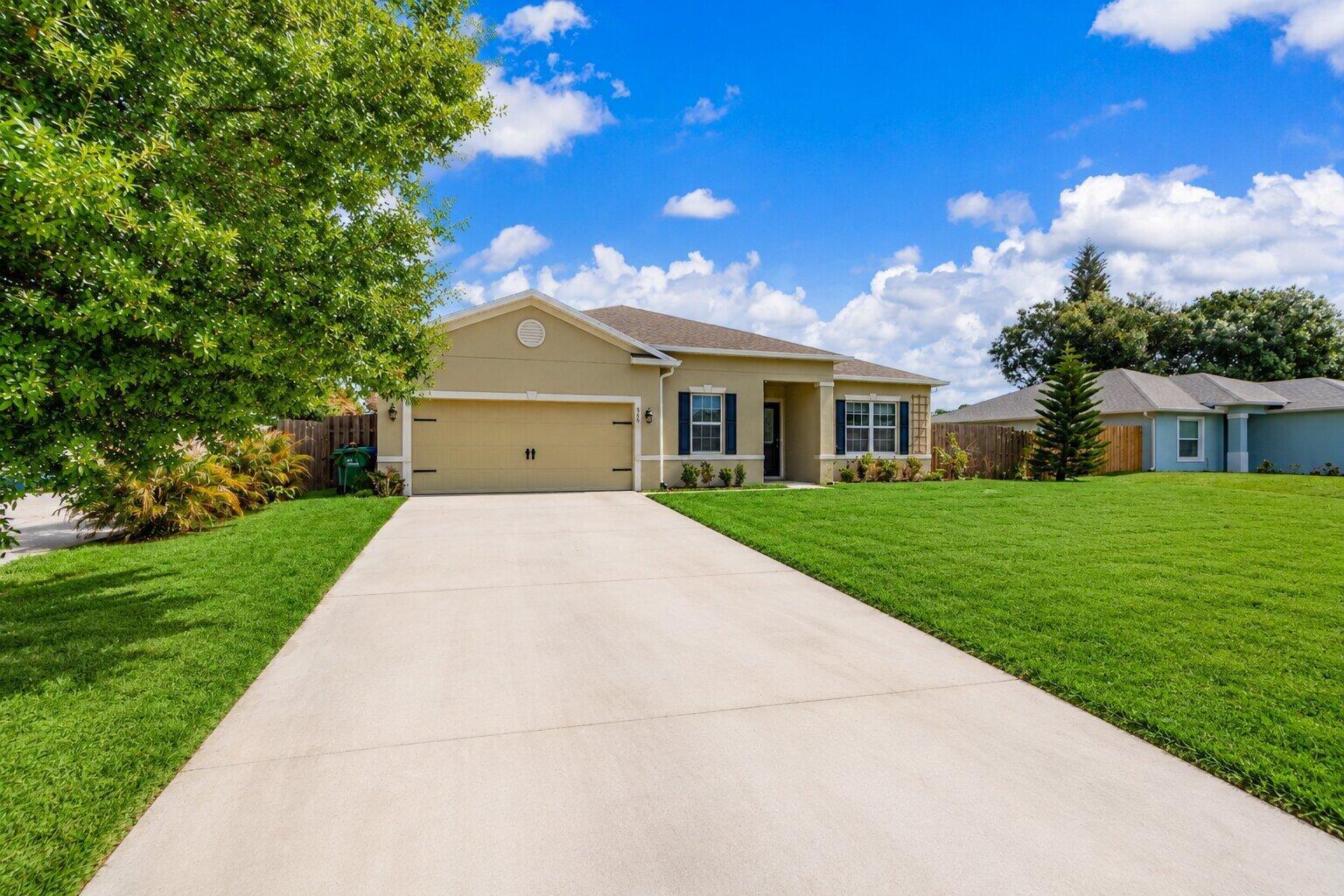 A single-story suburban house with a tan exterior, two-car garage, and a concrete driveway — 956 Claire Avenue, Sebastian FL 32958, SEBASTIAN, FL