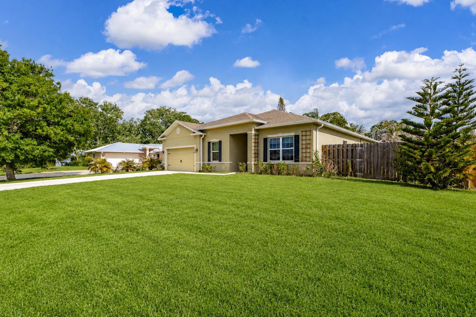 A single-story tan house with a two-car garage and a large front lawn — 956 Claire Avenue, Sebastian FL 32958, SEBASTIAN, FL