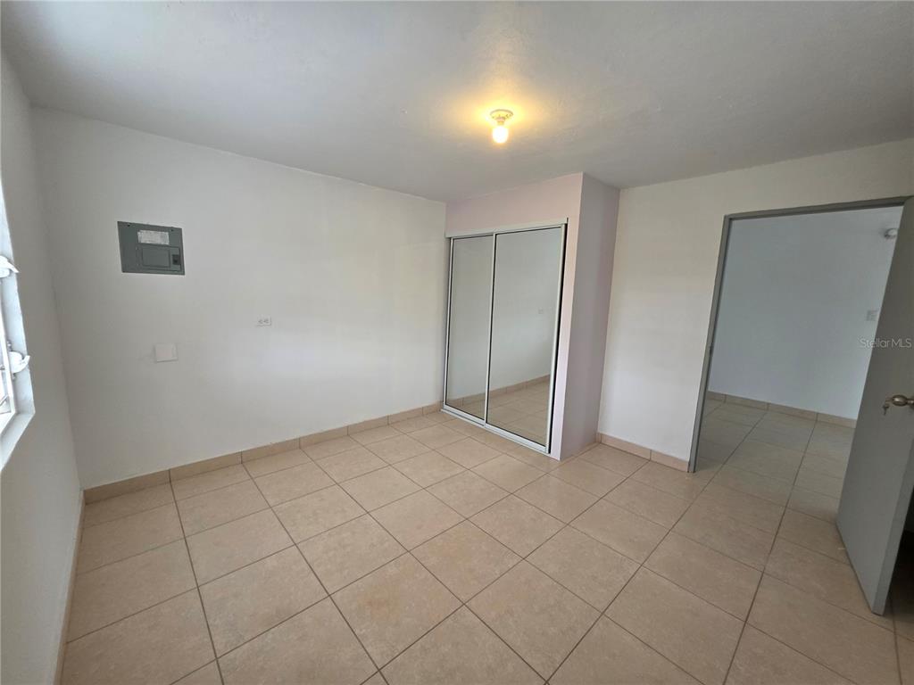 An empty room features white walls, tiled floors, a mirrored closet, and a doorway — 657 ST BO. ARRENALEJOS #4, ARECIBO, PR