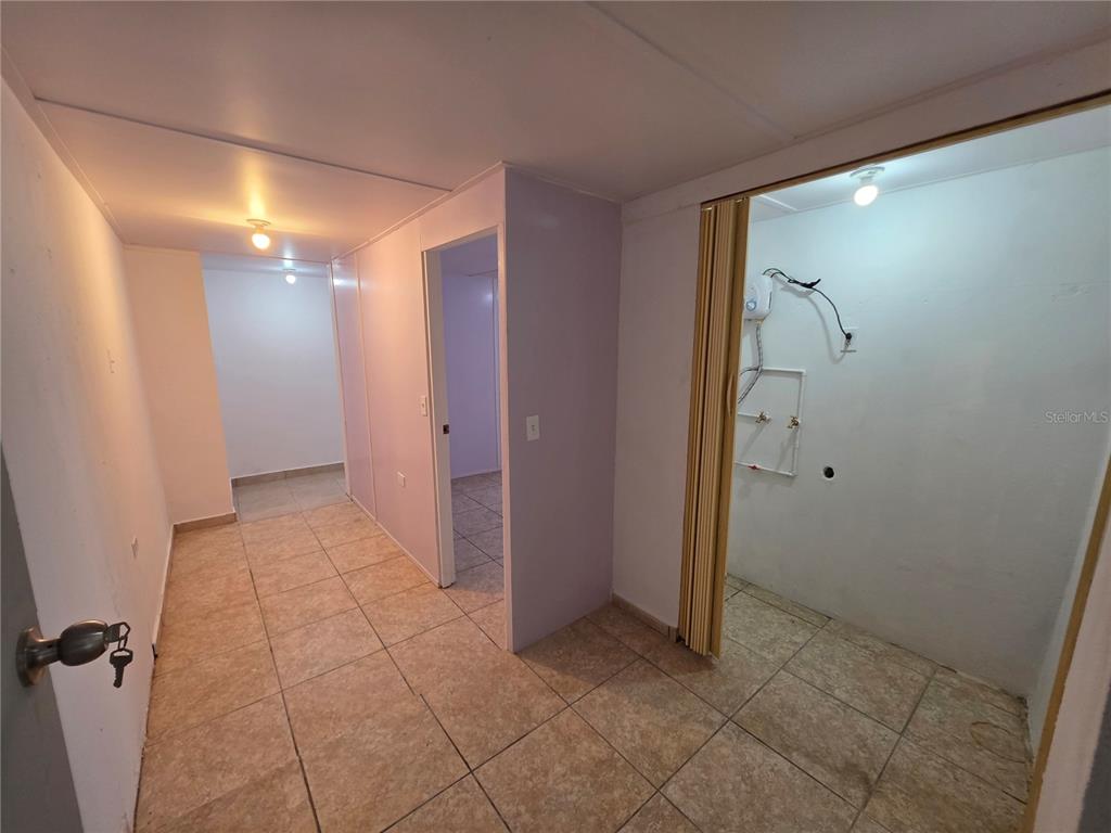 A tiled hallway leads to a doorway and a laundry area with exposed plumbing — 657 ST BO. ARRENALEJOS #4, ARECIBO, PR