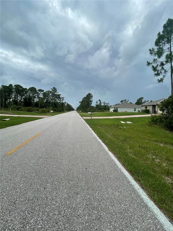 A paved road stretches into the distance past grassy lots and a suburban house — 3515 GILLOT BOULEVARD, PORT CHARLOTTE, FL