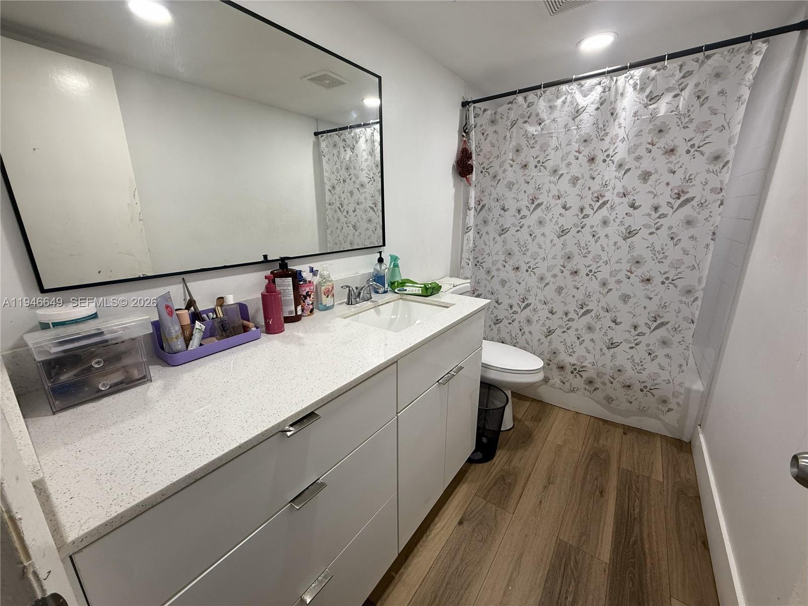 A bathroom features a white vanity with a speckled countertop, a large mirror, and a shower — 10822 N Kendall Dr # S23, Miami FL 33176, MIAMI, FL